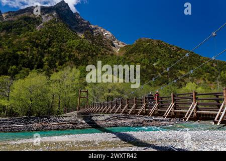 KAMIKOCHI, JAPAN - 24. MAI 2023: Wanderer überqueren die Myojin-Hängebrücke über den Azusa-Fluss in Kamikochi, Nagano, Japan Stockfoto