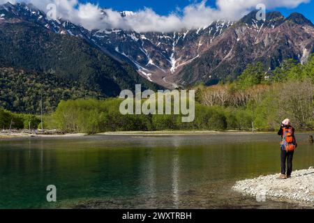 KAMIKOCHI, JAPAN - 24. MAI 2023: Wanderer neben einem Teich und dem Fluss Azusa mit schneebedeckten Bergen dahinter. Kamikochi, Präfektur Nagano Stockfoto