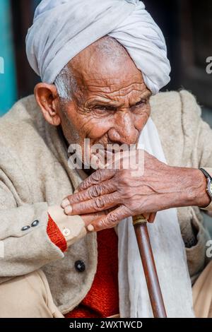 Älterer einheimischer Mann mit Turban, der eine Wasserpfeife raucht, im Dorf am Naddi Aussichtspunkt, berühmt für seine Aussicht auf die massive Dhauladhar Range Stockfoto