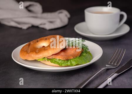 Lebensmittelfotografie von Bagel mit Räucherlachs, Sahne, Dill, Römersalat, Tee mit Milch, Sandwich, Morgen, Scheibe, Frühstück, Brunch Stockfoto