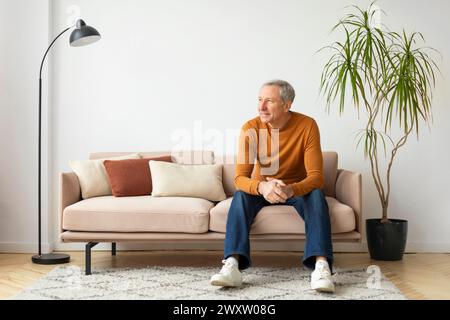 Mann sitzt auf Sofa in einem gemütlichen Wohnzimmer Stockfoto