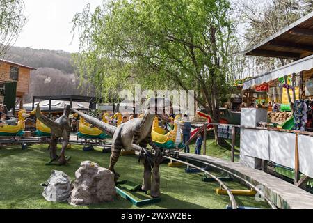 Kinder auf einer Dinosaurier-Achterbahn im Freien in einem Vergnügungspark in Österreich Stockfoto