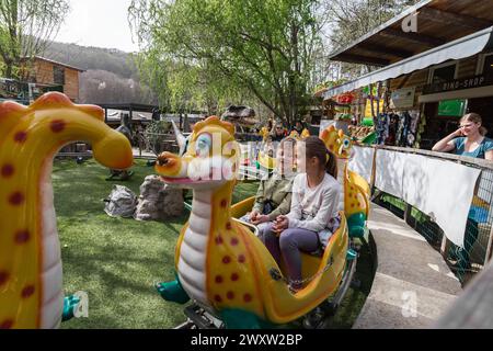 Kinder auf einer Dinosaurier-Achterbahn im Freien in einem Vergnügungspark in Österreich Stockfoto