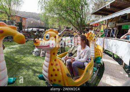 Kinder auf einer Dinosaurier-Achterbahn im Freien in einem Vergnügungspark in Österreich Stockfoto