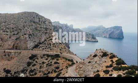 Einsames weißes Auto auf einer geschwungenen Asphaltstraße in der Nähe des Leuchtturms von Cap de Formentor Felsküste. Mallorca, Balearen, Spanien. Stockfoto