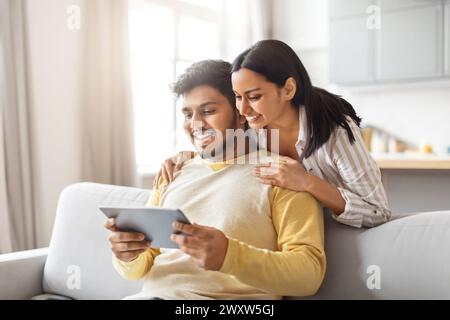 Indische Männer und Frauen sitzen auf der Couch und sehen Tablet an Stockfoto