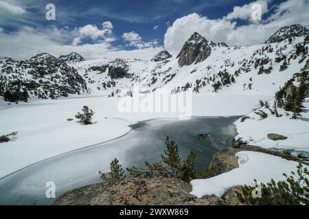 Pacific Crest Trail. Eine wunderschöne Bergkette mit einem See im Vordergrund. Der See ist gefroren und von Schnee umgeben. Der Himmel ist klar und blau Stockfoto