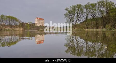 Historisches Schloss Plumlov aus dem 17. Jahrhundert und Reflexion auf der Oberfläche des Teiches im Bezirk Prostejov in Tschechien. Rauchluftverschmutzung Himmel. Stockfoto