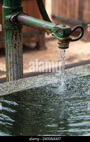 Eine Nahaufnahme des Wassers, das aus einem alten Gartenhahn oder Wasserhahn fließt. Stockfoto