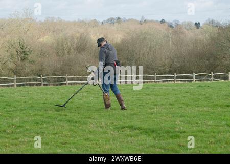 Ein Metalldetektor auf einem Feld, der nach Metallgegenständen sucht, die im Boden versteckt sind. Mann mit Metalldetektor. Stockfoto