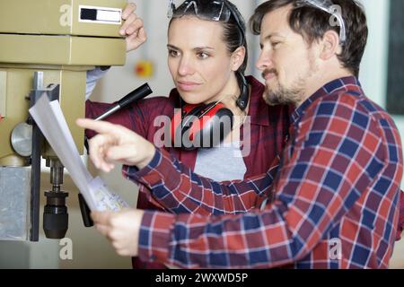 Mann und Frau mit NC-Steuerung der Maschine Stockfoto