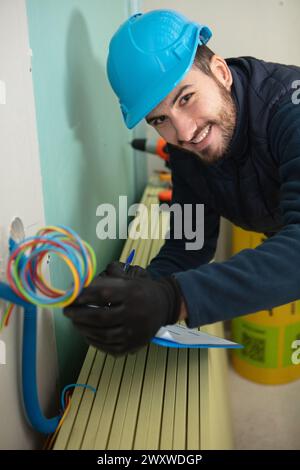 Elektriker überprüft elektrische Leitungen in der Wand Stockfoto