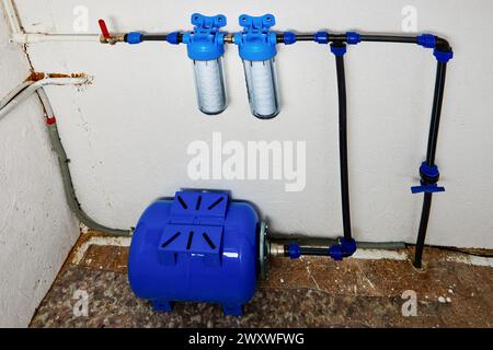 Umkehrosmose-Membran-Lagertank, Druckspeicher und Kartuschen mit Seilfiltern in der Hauswasserversorgung im Versorgungsraum. Stockfoto