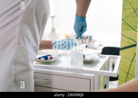 Zugeschnittene Aufnahme einer professionellen, nicht erkennbaren Krankenschwester, die den IV-Stab für den Patienten im Krankenhaus vorbereitet. Nahaufnahme der Hände eines Arztes, der Tropfen vorbereitet Stockfoto