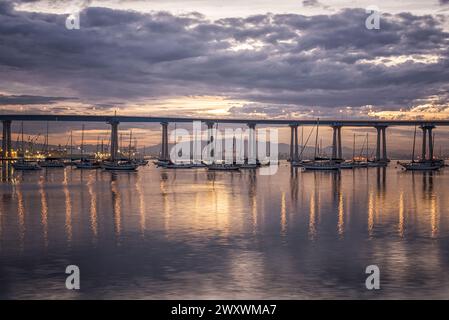 Bewölkter Sonnenaufgang in Coronado, Kalifornien, USA. Blick auf den Hafen von San Diego und die Coronado Bridge vom Tidelands Park. Stockfoto