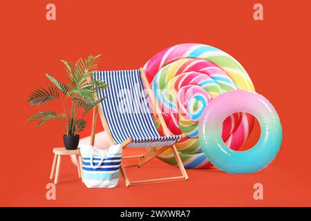 Schwimmmatratze in Form von Süßigkeiten, aufblasbarem Ring und Sonnenliege auf orangem Hintergrund Stockfoto