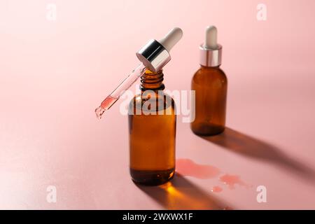 Pipette und Flaschen mit feuchtigkeitsspendendem Serum auf rosa Hintergrund Stockfoto