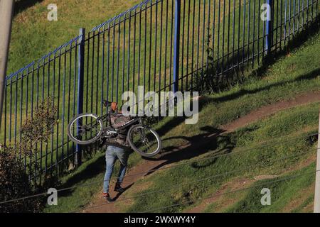 Bogota, Kolumbien, 24-01-2024. Ein Radfahrer klettert auf sein Fahrrad, lädt sein Fahrrad auf dem Rücken, während er einen Hügel hinaufklettert, um sein Zuhause in einem Viertel von Bogot zu erreichen Stockfoto