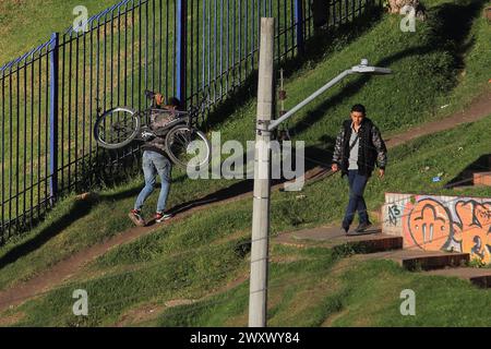 Bogota, Kolumbien, 24-01-2024. Ein Radfahrer klettert auf sein Fahrrad, lädt sein Fahrrad auf dem Rücken, während er einen Hügel hinaufklettert, um sein Zuhause in einem Viertel von Bogot zu erreichen Stockfoto