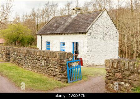 Traditionelles, weiß-blau bemaltes irisches Cottage mit einer Steinmauer und einem blau bemalten Tor Stockfoto