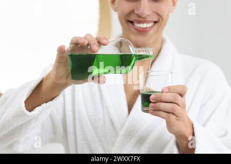 Junger Mann, der drinnen Mundspülung benutzt, Nahaufnahme Stockfoto