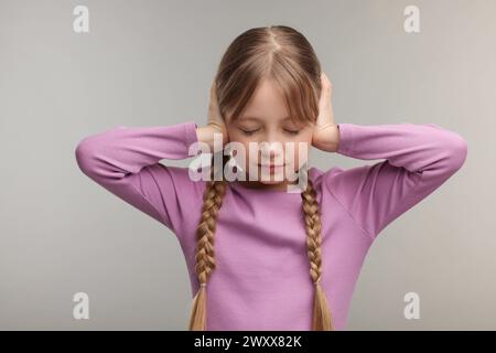 Hörprobleme. Kleines Mädchen mit Ohrenschmerzen auf grauem Hintergrund Stockfoto