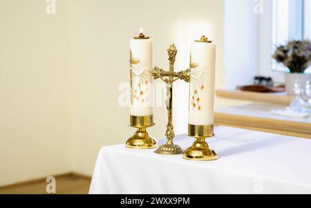 Holzkreuz, Schneeglöckchen, Blumen und Kerzen auf dem Tisch, abstrakter Hintergrund. Kirchliche Feiertage. Symbol des Glaubens an Gott, Christentum fest, Easte Stockfoto