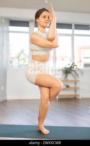 Fokussierte junge Yogalehrerin, die Garudasana durchführt Stockfoto