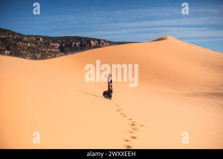 Frau, die auf einer Sanddüne in der Wüste im Coral Pink Sand Dunes State Park, Utah, spaziert Stockfoto