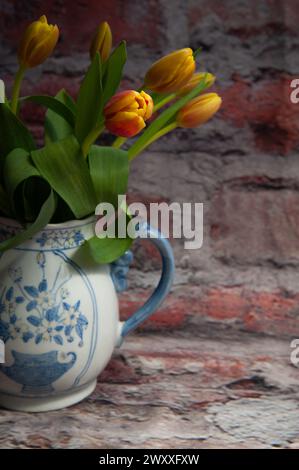 Gelbe und rote Tulpen in einer blauen Keramikvase Stockfoto