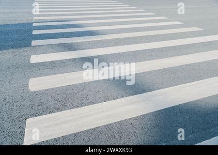 Fußgängerüberquerung, weiße Streifen auf schwarzem Asphalt, Straßenmarkierungen, Zebraüberquerung, Ort, an dem die Straße überquert wird, Verkehrsregeln Stockfoto