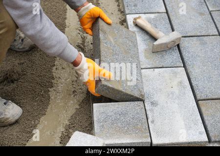 Ein Arbeiter, der Betonziegel aufeinander legt, um einen neuen Bürgersteig zu bauen Stockfoto