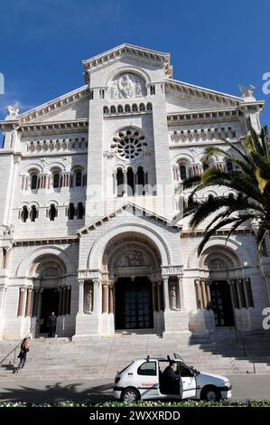 Kathedrale, Monte Carlo, Fürstentum Monaco, Vorderansicht eines Kirchengebäudes mit Palmen und einigen Leuten davor, Cote d'Azur Stockfoto