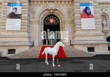 Haupteingang des Ozeanographischen Museums, Monte Carlo, Eine weiße Einhornskulptur vor einem historischen Gebäude mit rotem Teppich und Informationen Stockfoto