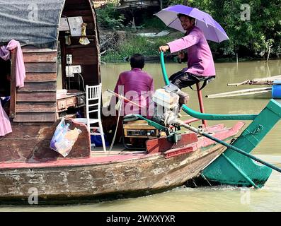 Ayutthaya, Thailand. 31. März 2024. Menschen auf einem Boot auf dem Pa Sak River schützen sich vor der Sonne mit Sonnenschirmen in der Nähe von Ayutthaya. Thailand erlebt derzeit ungewöhnlich hohe Temperaturen von über 40 Grad Celsius. Vermerk: Carola Frentzen/dpa/Alamy Live News Stockfoto