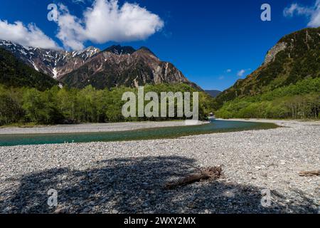 Breiter, klarer Fluss, der durch üppige Wälder fließt, mit hoch aufragenden Bergen im Hintergrund Stockfoto