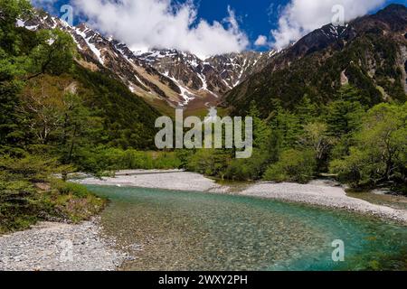 Schöner, klarer Fluss, der zu schneebedeckten Berggipfeln fließt (Kamikochi, Nagano, Japan) Stockfoto