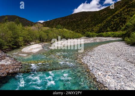 Schnell fließender, klarer Fluss, der durch einen Wald und Berge fließt Stockfoto