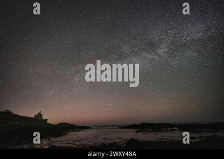 Aktenfoto vom 04/23 des Bade House in Howick, einem kleinen Häuschen, das an der Küste von Northumberland unter der Milchstraße liegt. Galaxien werden chaotischer, je älter sie werden, wie eine Studie vermutet. Laut den Forschungen ist das Alter die treibende Kraft für die Veränderung der Bewegung von Sternen innerhalb von Galaxien. Ausgabedatum: Mittwoch, 3. April 2024. Stockfoto