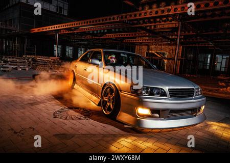 High Speed Night Drift mit maßgeschneidertem Sportwagen in urbaner Umgebung Stockfoto