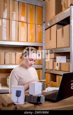 Junge Unternehmer Kleinunternehmen, die Internetbestellungen auf dem Smartphone überprüfen und verpackte Artikel für die Lieferung an Kunden vorbereiten. Stockfoto