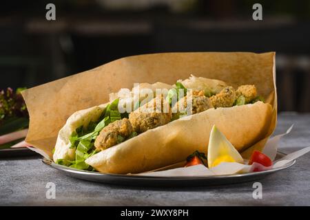 Frittierte Muscheln in Brot und mit Gemüse an der Seite. Türkischer Name Midye Tava Stockfoto