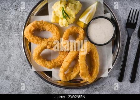 Gebratene Calamari mit Kartoffelsalat daneben auf Steintisch Stockfoto
