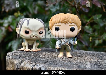 Funko Pop Actionfiguren von Gollum und Hobbit Sam aus dem Fantasy-Film der Herr der Ringe. Dunkler Wald, Baumstumpf, grüne Blätter. Stockfoto