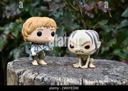 Funko Pop Actionfiguren von Hobbit Sam und Gollum aus dem Fantasy-Film der Herr der Ringe. Dunkler Wald, Baumstumpf, grüne Blätter. Stockfoto