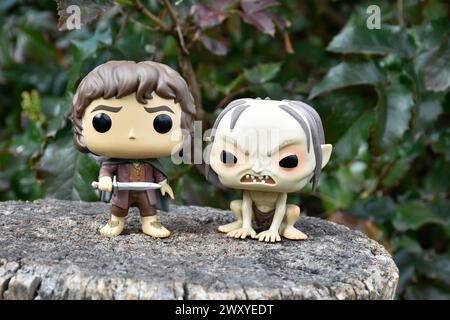 Funko Pop Actionfiguren von Hobbit Frodo und Gollum aus dem Fantasy-Film der Herr der Ringe. Dunkler Wald, Baumstumpf, grüne Blätter. Stockfoto