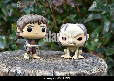 Funko Pop Actionfiguren von Hobbit Frodo und Gollum aus dem Fantasy-Film der Herr der Ringe. Dunkler Wald, Baumstumpf, grüne Blätter. Stockfoto