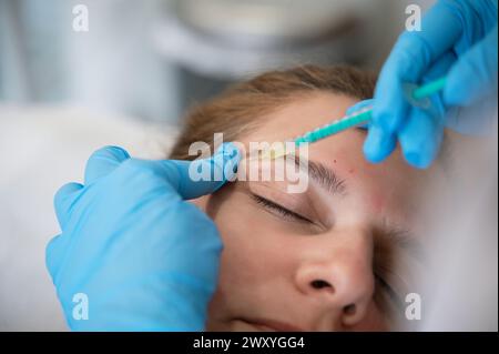 Frau, die während der Verjüngungsbehandlung in der Klinik eine Gesichtsinjektion erhält Stockfoto