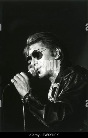 Reims (Nordostfrankreich), 1993: Jacques Dutronc im Konzert, mit schwarzer Sonnenbrille und Lederjacke, die sein Mikrofon hält Stockfoto