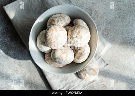 Eine Schüssel mit traditionellen Keksen, die mit Puderzucker bestäubt sind und auf einer texturierten Tischdecke serviert werden Stockfoto